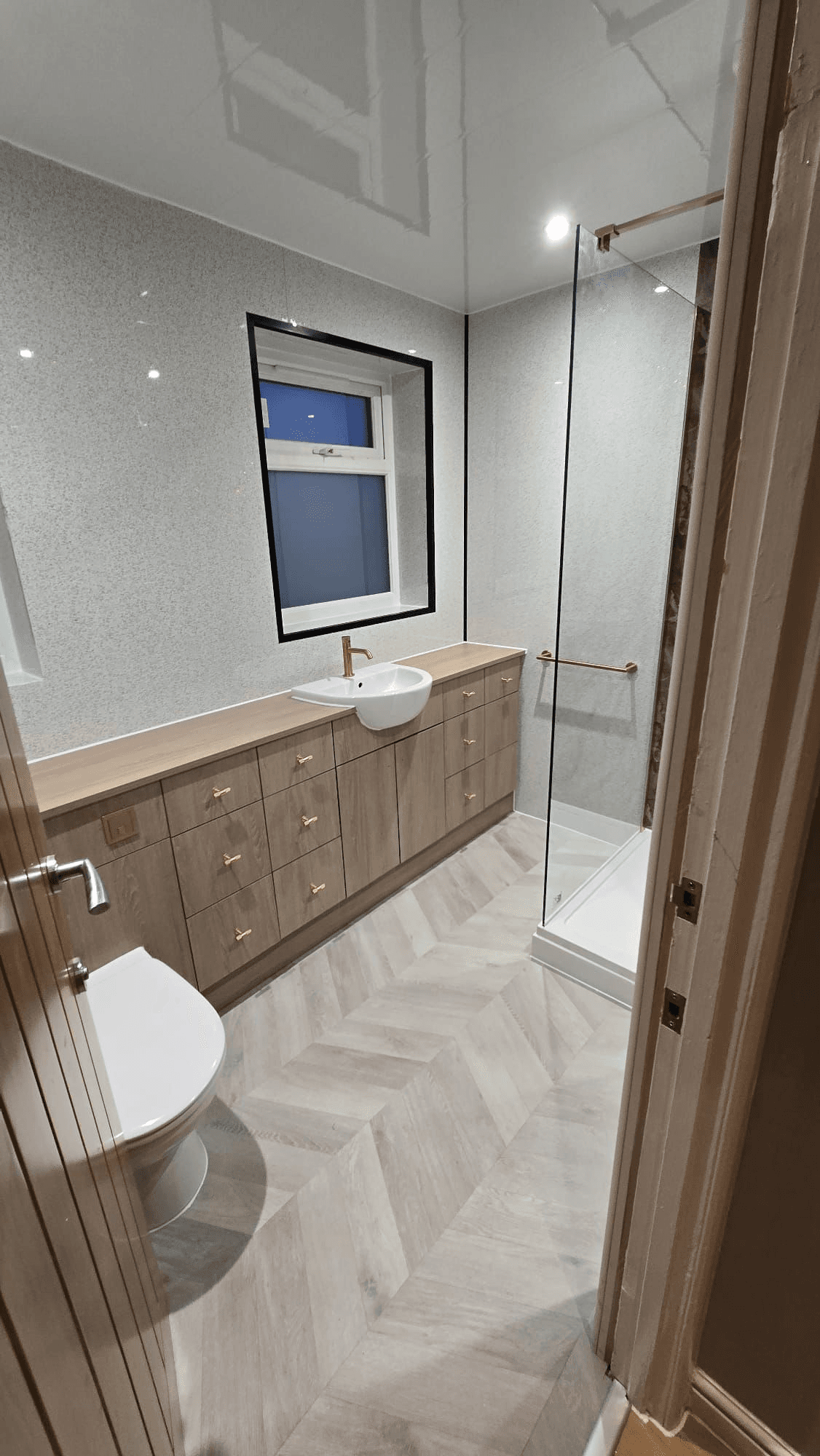 Bathroom with gold fixtures, vanity unit and herringbone floor