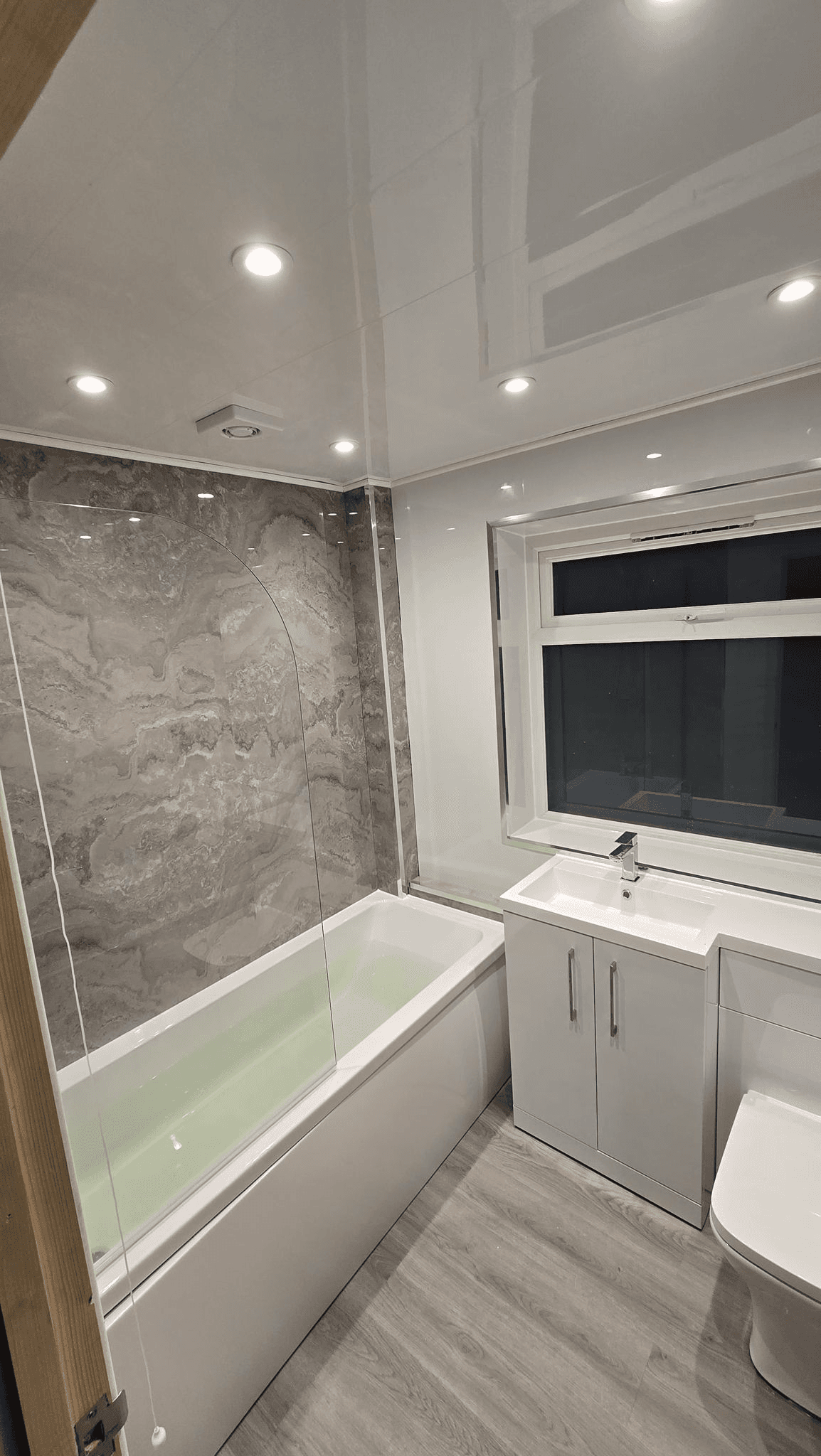 Bathroom with marble effect panels and fitted bath
