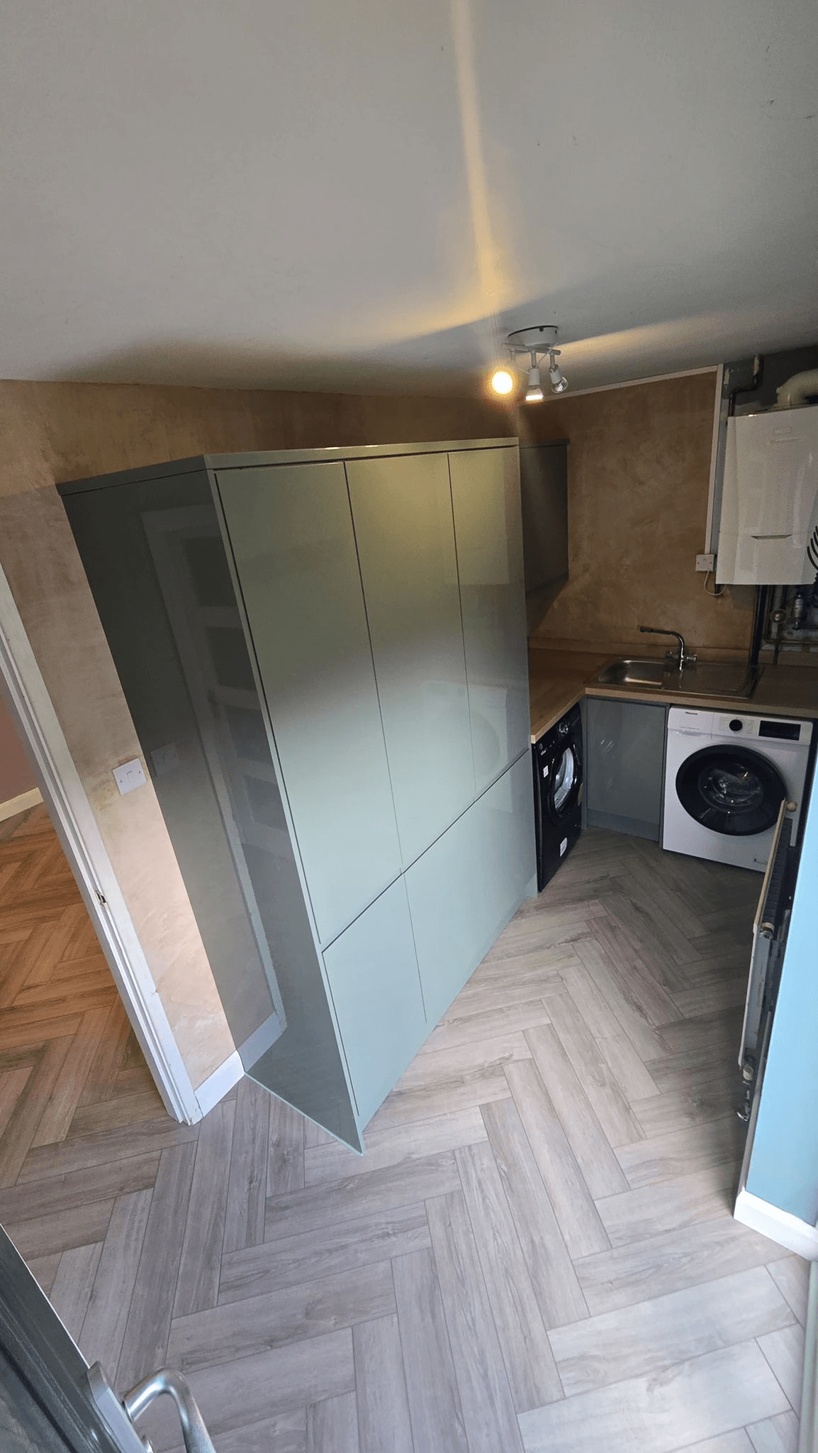 Kitchen utility room with sage green cabinets and herringbone floor